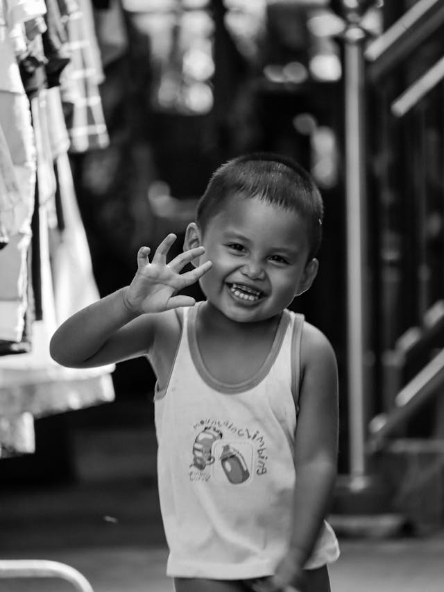Friendly Filipino local child smiling and waving from a traditional store.