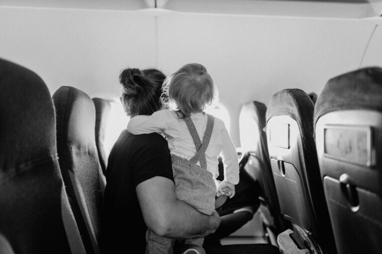 Parent seated with toddler looking out the plane window